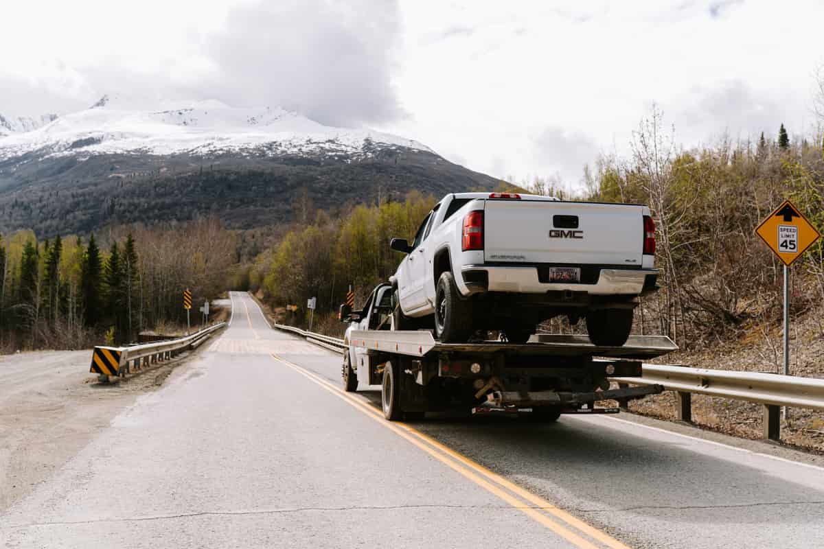Loaded flatbed tow truck traveling on a two-lane Alaska highway