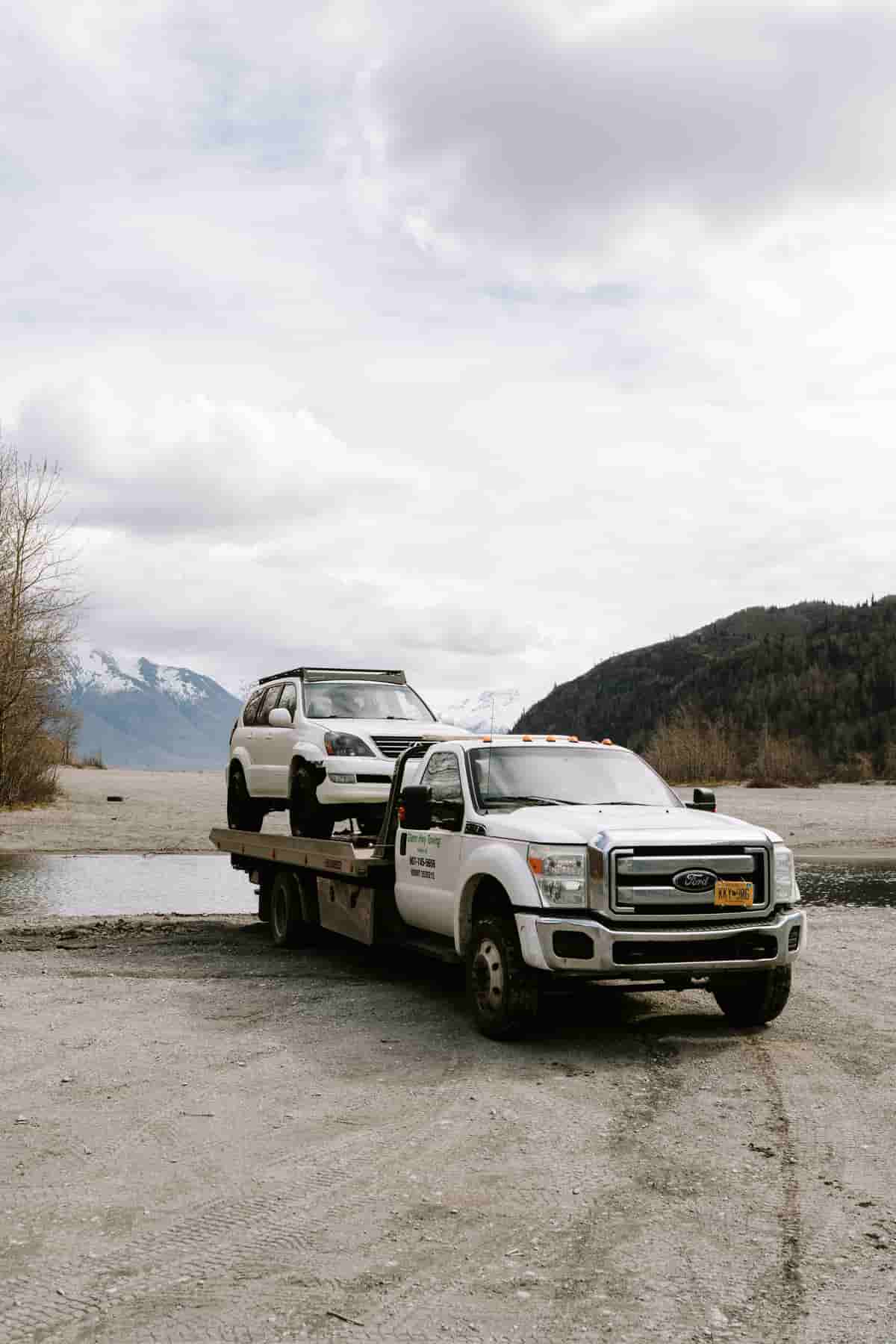 SUV secured on a flatbed beside an Alaska mountain road